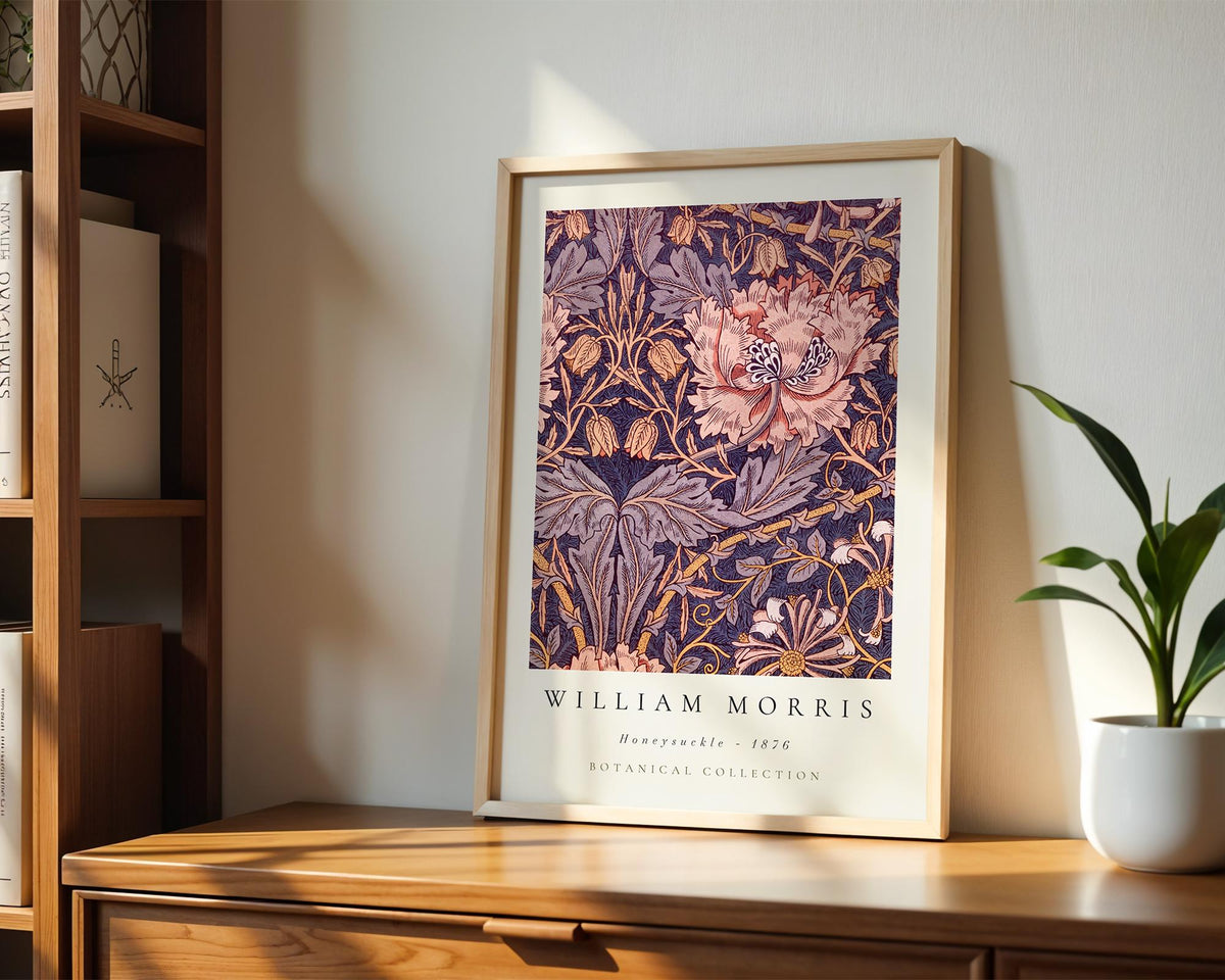 A framed poster of William Morris' botanical collection from 1826 is displayed on a wooden shelf, accompanied by a potted plant and a bookshelf.