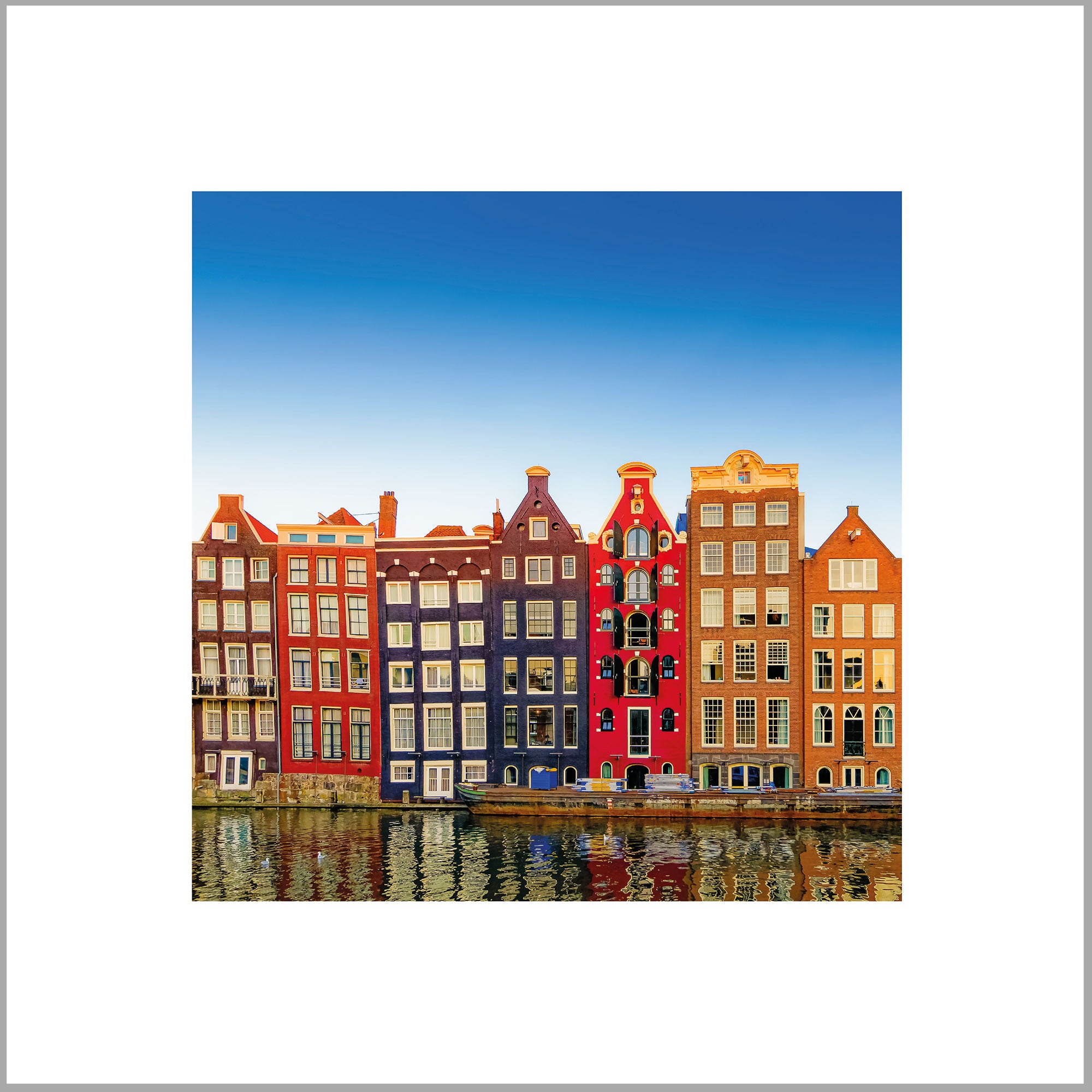 A row of colorful, traditional Dutch houses lining the waterfront, with their reflections visible in the calm water below.