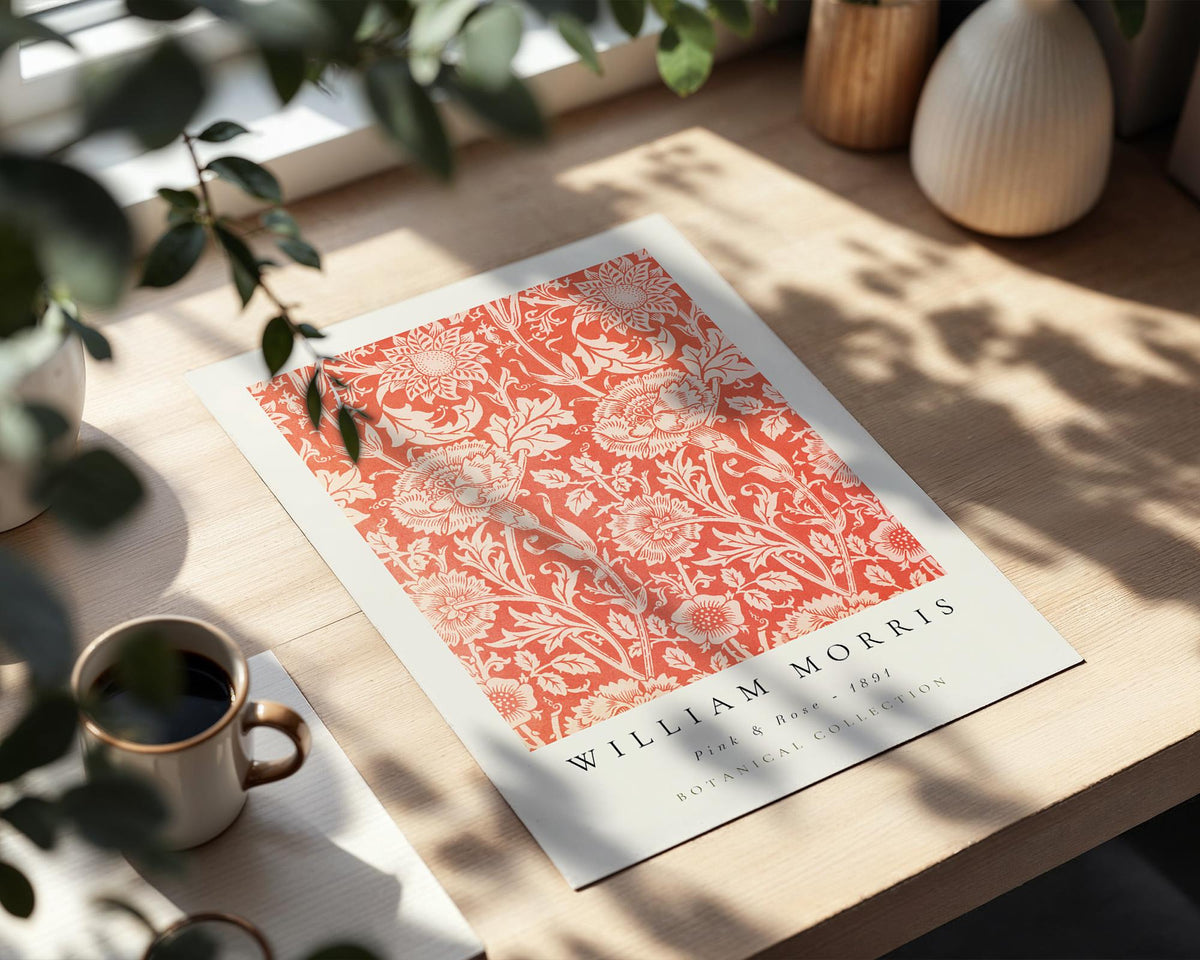 a poster with a floral pattern on a wooden surface, accompanied by a cup of coffee and a plant.