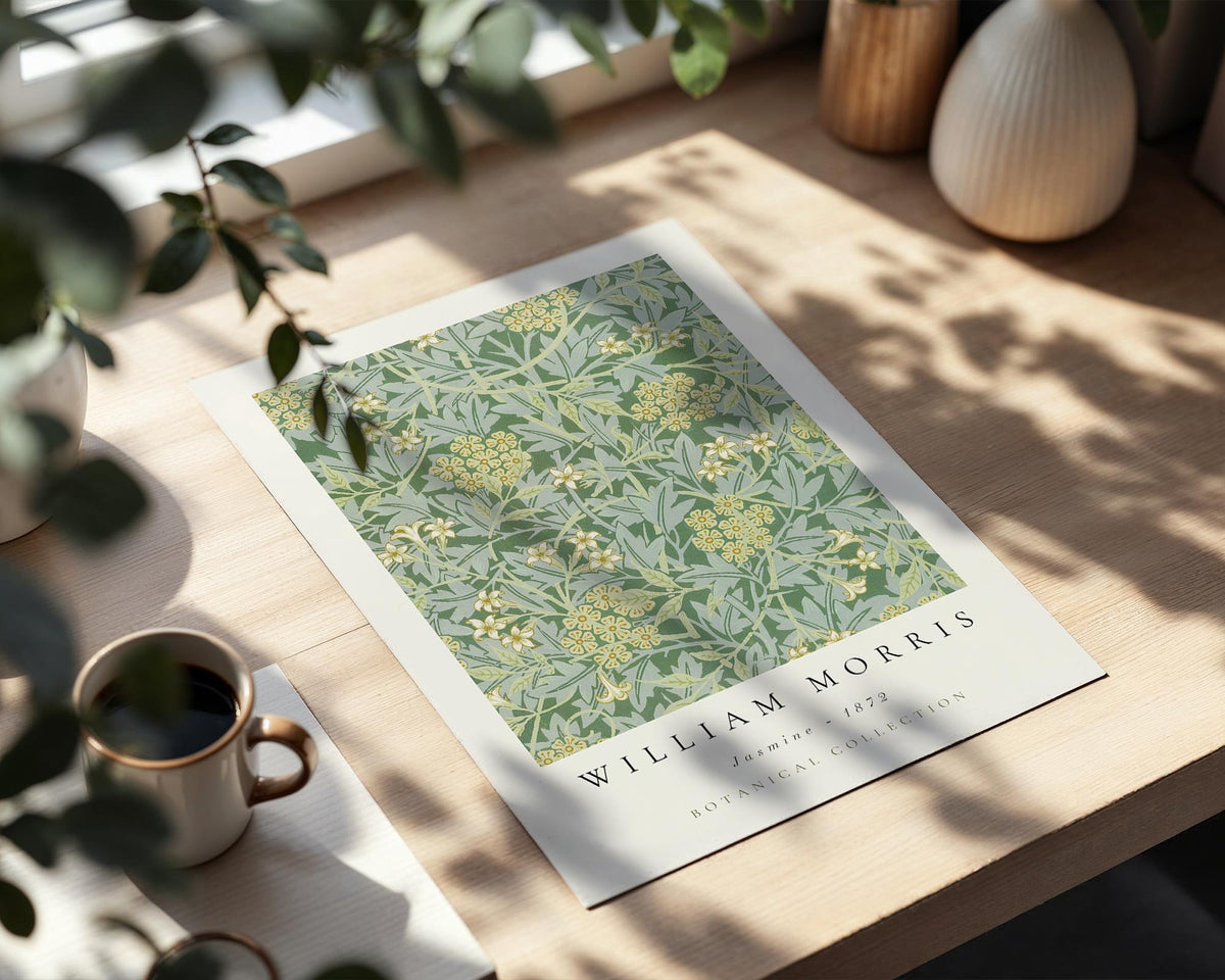 a poster of William Morris' botanical collection from 1872, placed on a wooden table next to a cup of coffee and some decorative items.