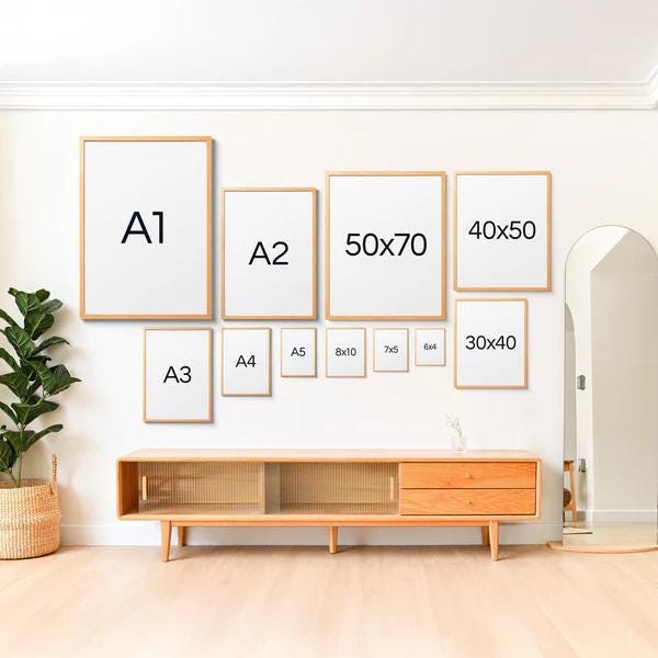a wall with a collection of framed artworks and a wooden entertainment center, creating a visually appealing and organized display.